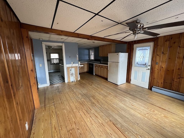 kitchen featuring a drop ceiling, wood walls, a ceiling fan, light wood-type flooring, and freestanding refrigerator