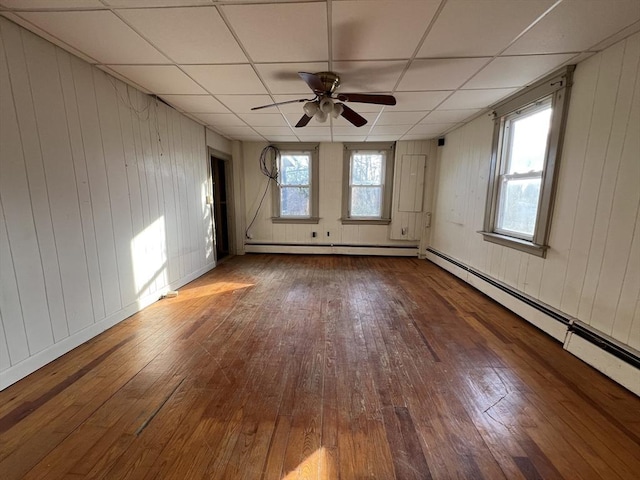 spare room with a baseboard heating unit, a drop ceiling, and hardwood / wood-style floors