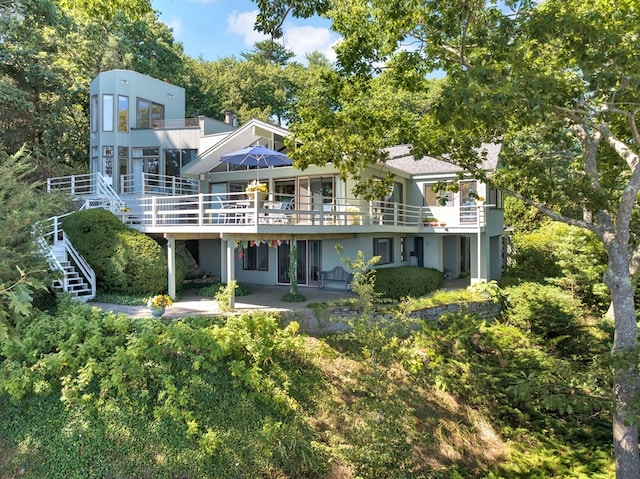 rear view of property featuring a wooden deck and a patio area