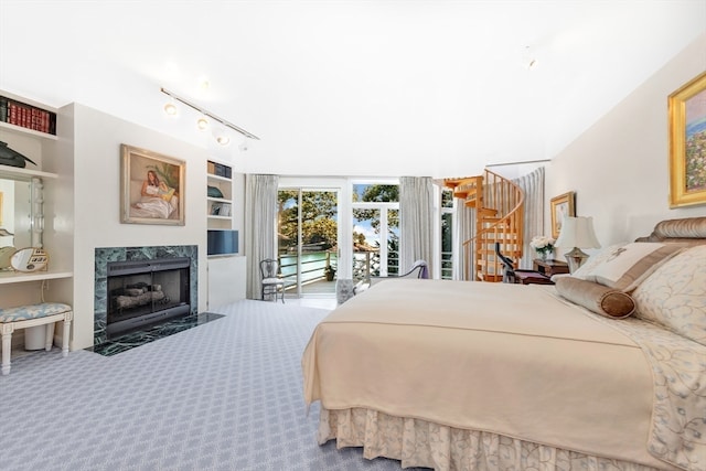 carpeted bedroom featuring a high end fireplace, track lighting, and access to outside