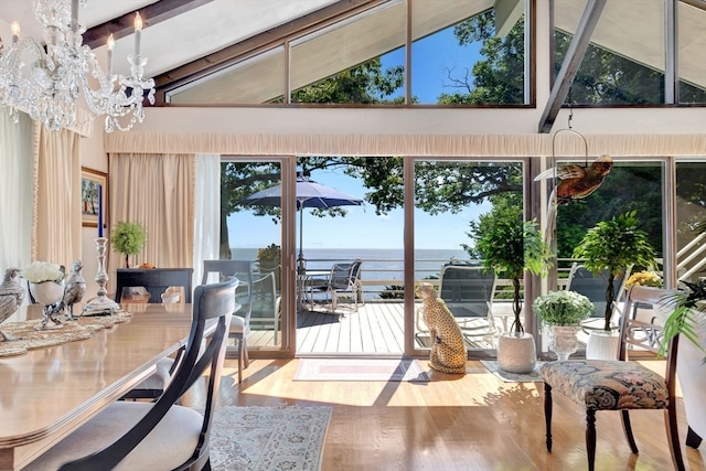 dining space with hardwood / wood-style flooring, a notable chandelier, a water view, and high vaulted ceiling