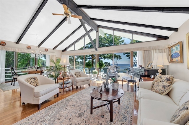 living room featuring hardwood / wood-style flooring, ceiling fan with notable chandelier, beam ceiling, high vaulted ceiling, and a water view