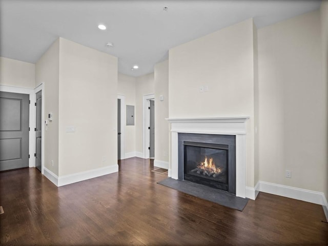 unfurnished living room with electric panel, a glass covered fireplace, baseboards, and wood finished floors