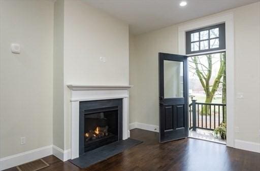 unfurnished living room featuring baseboards, wood finished floors, a glass covered fireplace, and recessed lighting