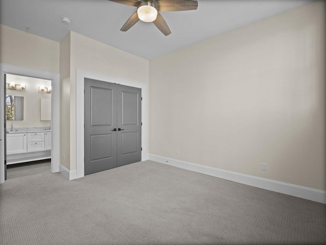 unfurnished bedroom featuring carpet flooring, a sink, baseboards, a closet, and connected bathroom