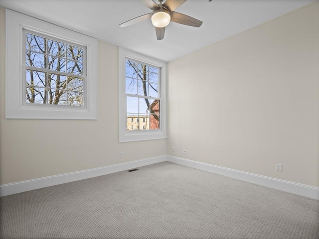 carpeted empty room with ceiling fan, baseboards, and visible vents