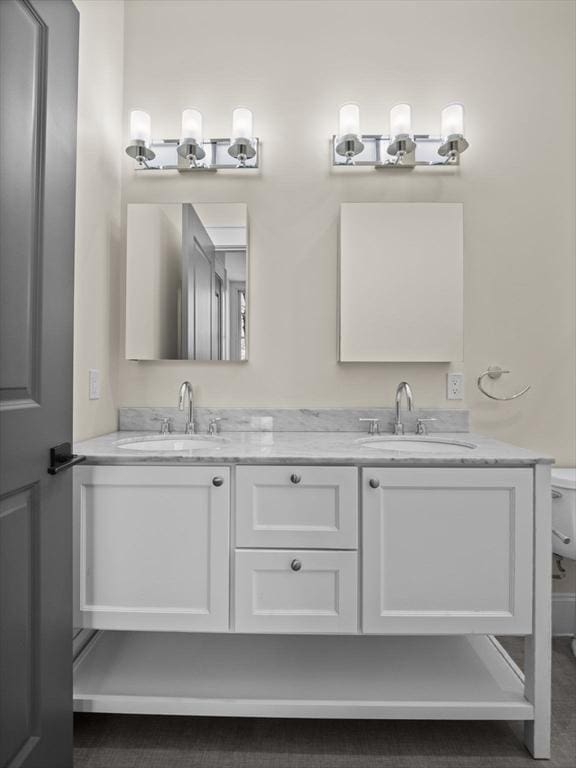 bathroom featuring toilet, a sink, and double vanity