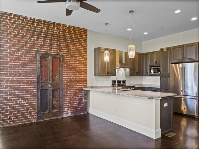 kitchen featuring a ceiling fan, a sink, stainless steel appliances, wall chimney exhaust hood, and dark wood-type flooring