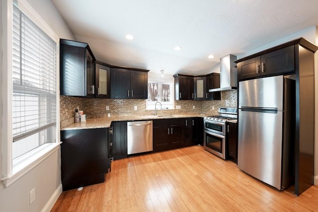 kitchen featuring sink, extractor fan, appliances with stainless steel finishes, light stone countertops, and backsplash