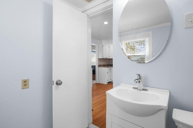 half bath featuring vanity, recessed lighting, wood finished floors, and toilet