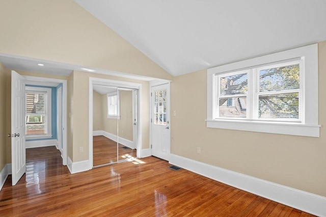 entryway featuring baseboards, lofted ceiling, light wood finished floors, and visible vents