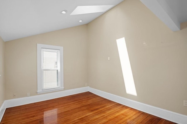 spare room with light wood-style floors, baseboards, and lofted ceiling with skylight