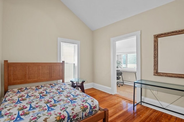 bedroom with baseboards, vaulted ceiling, and light wood-type flooring