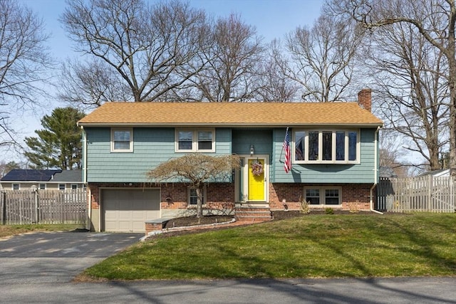 bi-level home with a chimney, a front lawn, aphalt driveway, fence, and entry steps