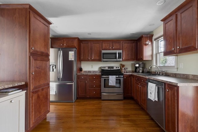 kitchen featuring stainless steel appliances, a sink, recessed lighting, and dark wood finished floors