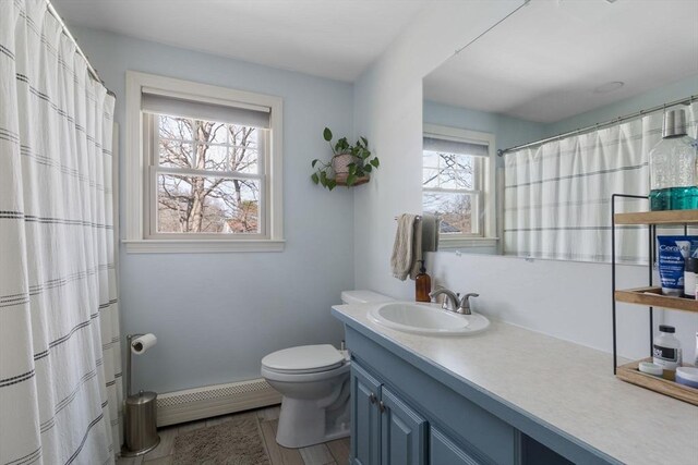 full bath featuring vanity, curtained shower, a baseboard radiator, and toilet