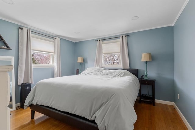 bedroom featuring wood finished floors, crown molding, and baseboards