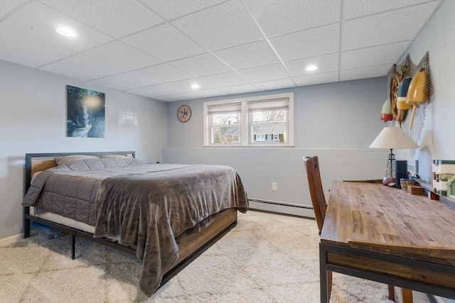 bedroom with a baseboard heating unit, baseboards, a paneled ceiling, and carpet flooring