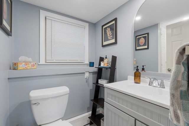 half bathroom featuring a baseboard heating unit, toilet, and vanity