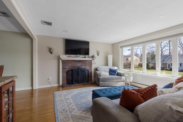 living room featuring baseboards, wood finished floors, visible vents, and a fireplace