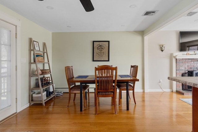 dining room with baseboards, a ceiling fan, visible vents, and light wood-type flooring