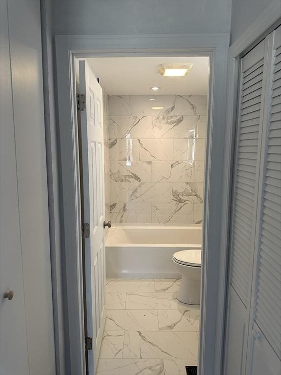 full bathroom featuring marble finish floor, toilet, and bathing tub / shower combination