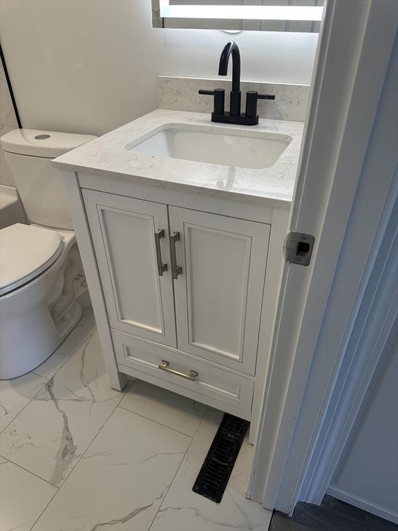 bathroom featuring marble finish floor, toilet, and vanity