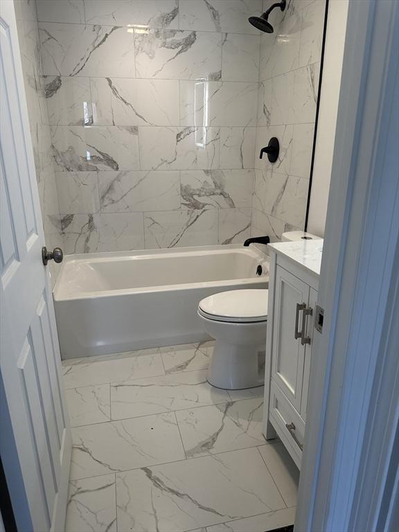 bathroom with marble finish floor,  shower combination, toilet, and vanity