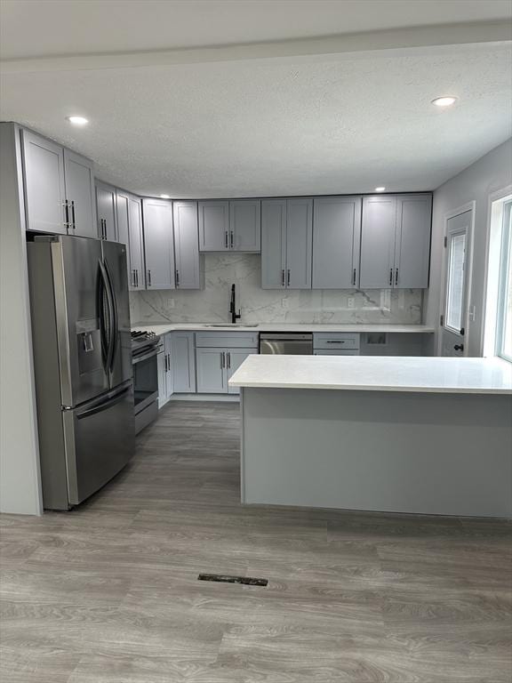 kitchen featuring light countertops, a sink, light wood-style floors, and appliances with stainless steel finishes