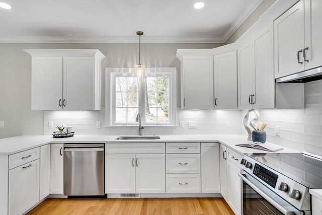 kitchen featuring stainless steel appliances, ornamental molding, a sink, and light countertops