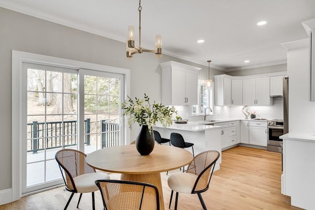 dining space featuring recessed lighting, a notable chandelier, crown molding, and light wood-style flooring