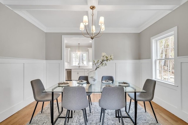 dining space with a chandelier, wainscoting, crown molding, and light wood-style flooring