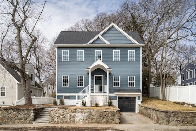 colonial home with concrete driveway, a shingled roof, an attached garage, and fence