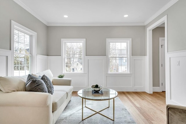 living area featuring wainscoting, light wood-style flooring, and a healthy amount of sunlight