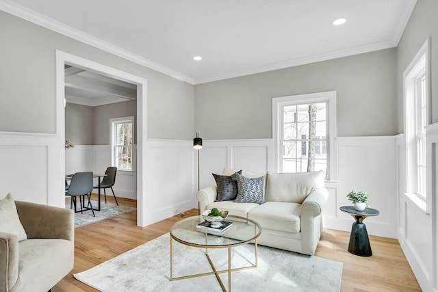 living area with light wood-style floors, a wealth of natural light, and a wainscoted wall