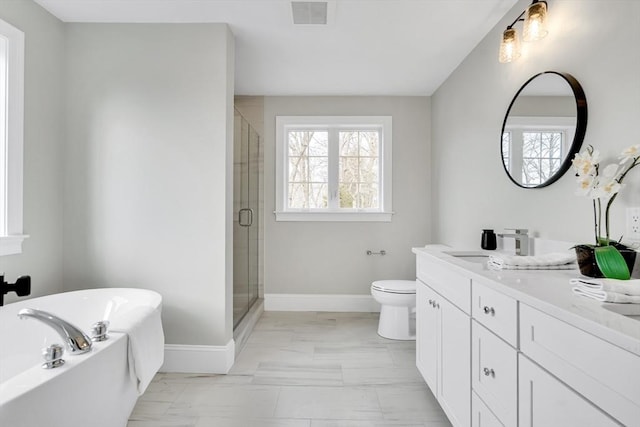 bathroom with a washtub, visible vents, plenty of natural light, and toilet