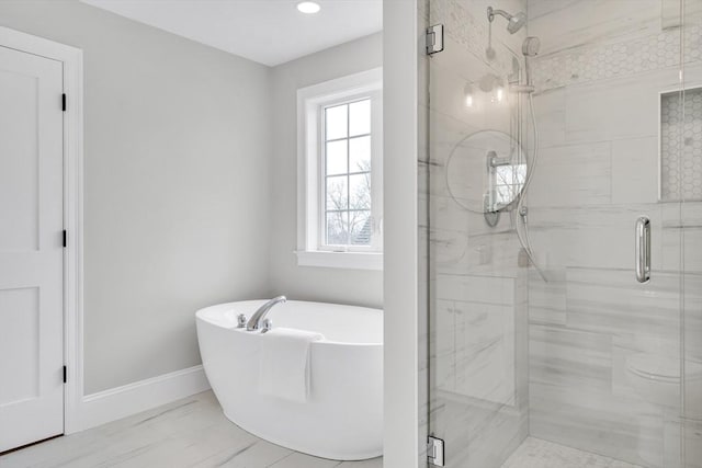 full bathroom featuring marble finish floor, a stall shower, a soaking tub, and baseboards