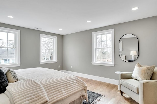 bedroom featuring multiple windows, light wood-type flooring, visible vents, and baseboards