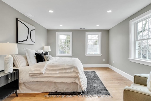 bedroom with light wood-style flooring, multiple windows, baseboards, and recessed lighting