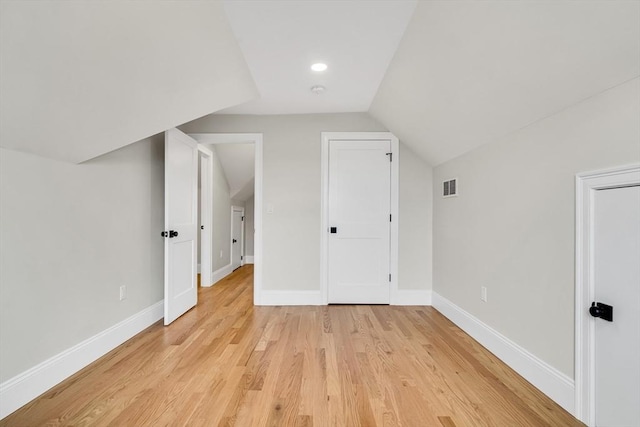 additional living space with baseboards, vaulted ceiling, visible vents, and light wood-style floors