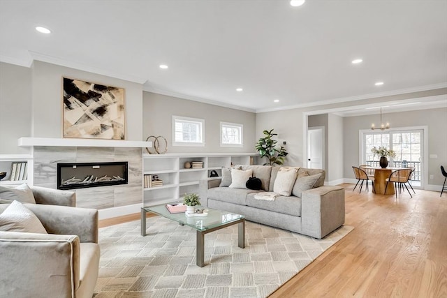 living room with ornamental molding, a wealth of natural light, light wood-style flooring, and baseboards