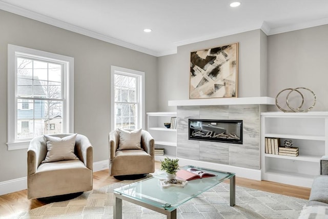 living area with ornamental molding, a tiled fireplace, wood finished floors, and baseboards