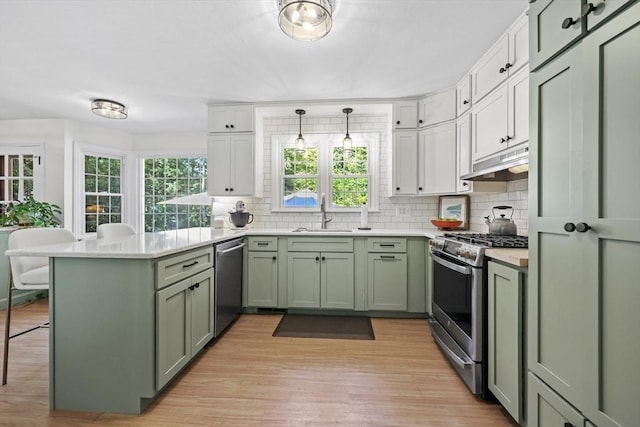 82 Knollwood Dr, Longmeadow, MA 01106 - kitchen with green cabinetry, appliances with stainless steel finishes, a peninsula, under cabinet range hood, and tasteful backsplash