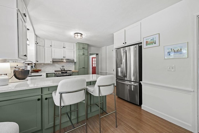 82 Knollwood Dr, Longmeadow, MA 01106 - kitchen with appliances with stainless steel finishes, green cabinetry, a peninsula, dark wood-style floors, and decorative backsplash