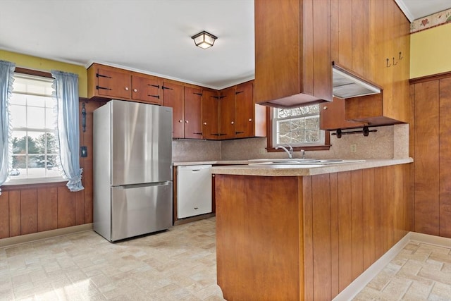 kitchen with dishwasher, decorative backsplash, sink, stainless steel fridge, and kitchen peninsula