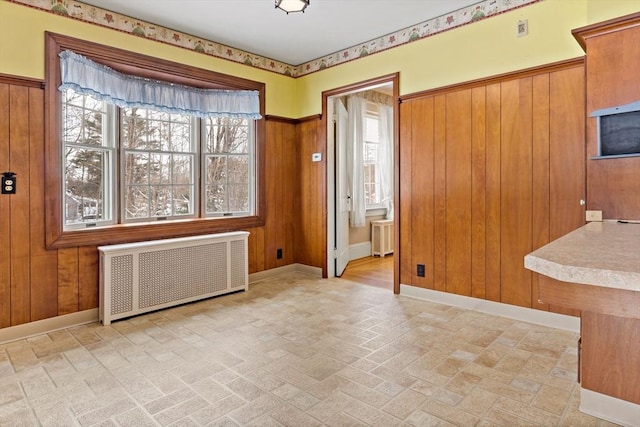 interior space featuring radiator, wood walls, and built in desk