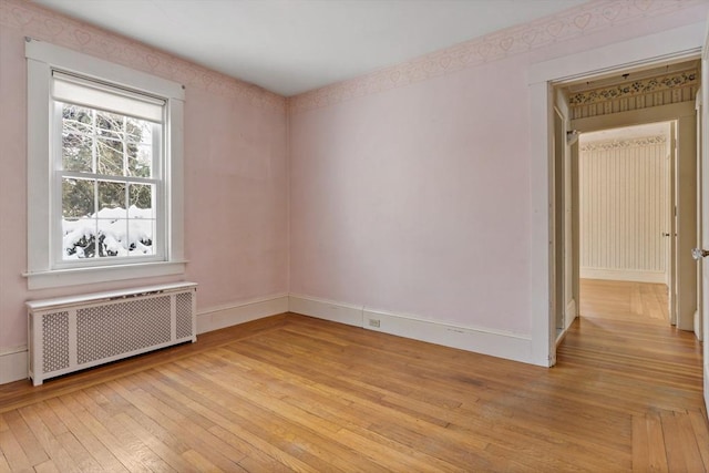 empty room featuring light wood-type flooring and radiator