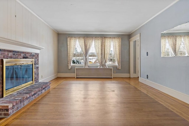 unfurnished living room with light hardwood / wood-style flooring, radiator heating unit, a brick fireplace, and ornamental molding