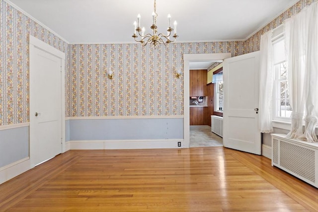 interior space with radiator heating unit, light hardwood / wood-style flooring, a notable chandelier, and ornamental molding