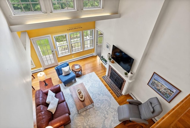 1 Emerson Dr, Acton, MA 01720 - living area with a baseboard heating unit, a fireplace with flush hearth, wood finished floors, and a high ceiling